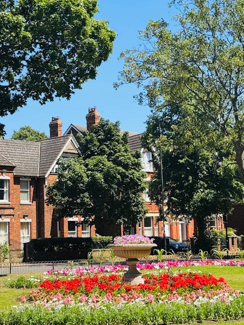 A neatly maintained front garden along Salusbury Road featuring a lush green lawn with evenly trimmed grass, bordered by a variety of plants and shrubs. The garden beds contain flowering plants and sm